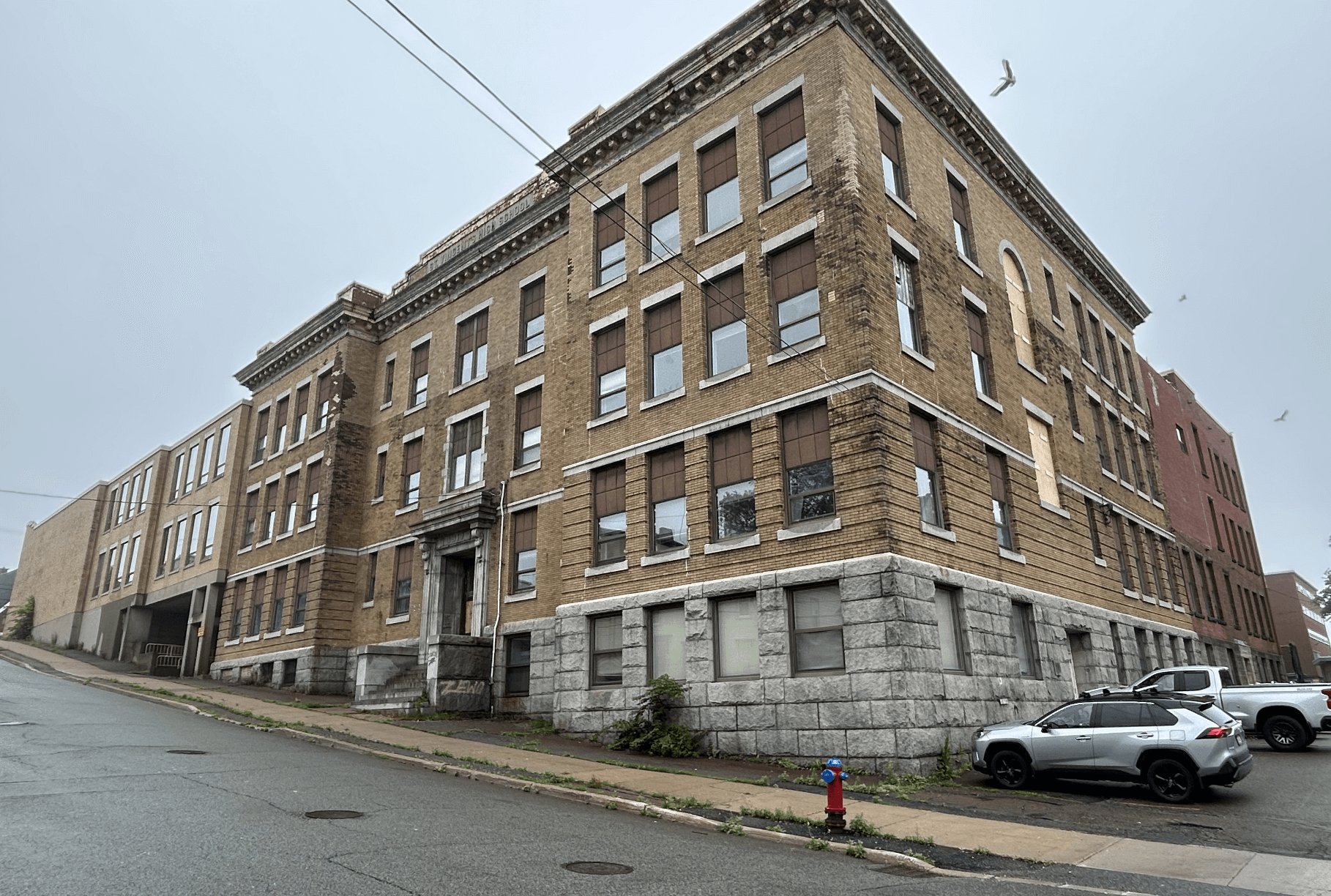 A three storey apartment building on a slightly sloped street with basement windows visible.